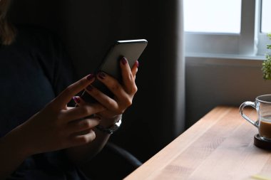 Genç bir kadın sosyal ağda sohbet ediyor ya da akıllı telefonuyla internetten alışveriş yapıyor..