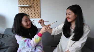 Mutlu Asyalı kardeşler evde birlikte nefes nefese kalmaktan hoşlanırlar. Kardeş ilişkileri kavramı.