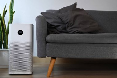 Oturma odasının ahşap zemininde dijital monitör ekranlı hava temizleyicisi evdeki toz PM2.5 'i filtreleyip temizliyor..