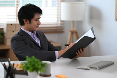 Odaklanmış iş adamı ofis odasındaki mali belgeleri kontrol ediyor.. 