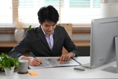 Genç finans piyasa analisti, modern, parlak işyerinde bilgisayarla çalışıyor..