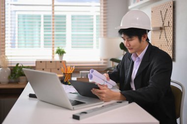 Yakışıklı Mimar erkek dijital tablet kullanıyor ve ofiste mimari plan üzerinde çalışıyor..