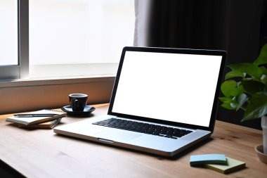 Laptop bilgisayarı, yapışkan notlar, saksı bitkisi ve kahve fincanı ahşap masada..