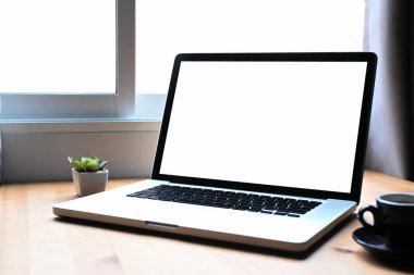 Laptop bilgisayarı, kahve fincanı ve ahşap masa üzerinde saksı bitkisi olan basit bir iş yeri..