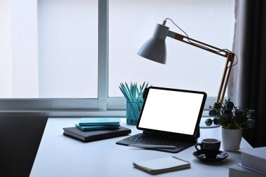 Bilgisayar tableti, lamba, saksı ve kırtasiyeli ofis masası..