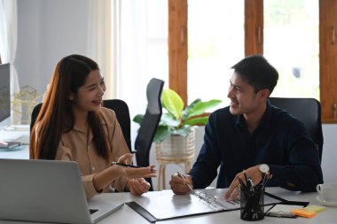İki iş ortağı proje stratejisini tartışırken mali veri raporunda birlikte sohbet ediyorlar..