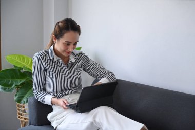 Çekici genç kadın kanepeye uzanıyor ve dijital tablet kullanıyor..