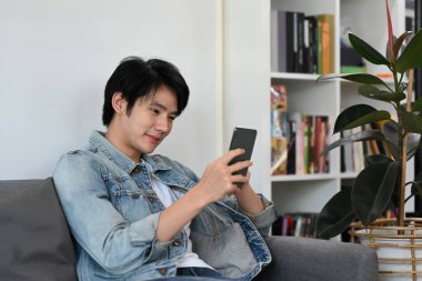 Mutlu Asyalı adam cep telefonunu e-posta ya da sosyal medyayı kontrol etmek için kullanıyor..