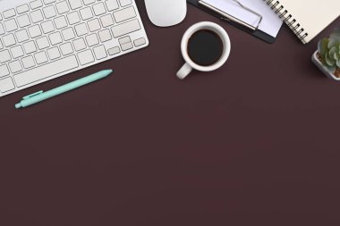 Mor zemin üzerinde düz kablosuz klavye, fare, kahve fincanı ve defter vardı..