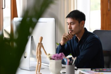 Odaklanmış finansör ofis masasındaki bilgisayarda mali işlemleri kontrol ediyor..