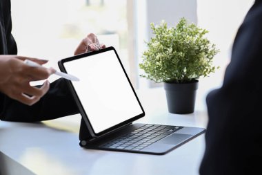 İş ortağıyla fikir paylaşımı için dijital tablet veya iş planı gösteren kırpılmış iş kadını.