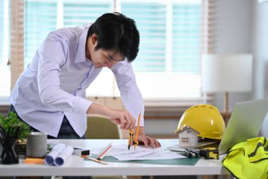 Profesyonel erkek mimar, mimari ekipmanlarla plan çiziyor..