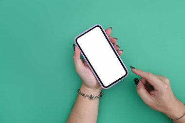 Yeşil arkaplanda boş ekranlı akıllı telefonu tutan kadının görüntüsü.