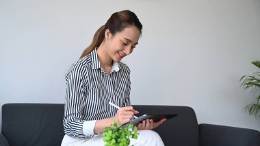 Kanepede oturup dijital tabletle çalışan güzel bir kadın serbest yazar..