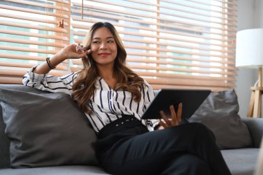 Dijital tabletle sosyal ağda gevşeyen ve sohbet eden gülümseyen genç kadın..