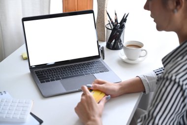 Omzunda bin yıllık kredi kartı olan ve dizüstü bilgisayar kullanan kadına bak.