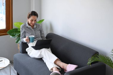 İnternet bankacılığı hizmetini kullanan güzel genç bir kadın evdeki bilgisayar tabletinden bilgi arıyor..