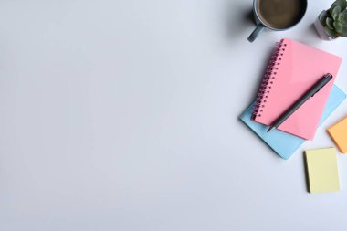 Not defterleri, kahve fincanı ve renkli yapışkan notları olan yaratıcı bir iş yeri. Metnin için boşluk kopyala.