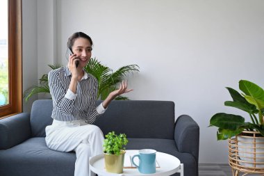 Güzel genç bayan rahat bir koltukta dinleniyor ve cep telefonuyla konuşuyor..