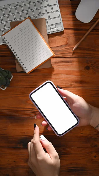 Yukarıda Ahşap Masada Beyaz Ekranlı Cep Telefonu Tutan Bir Kadın — Stok fotoğraf