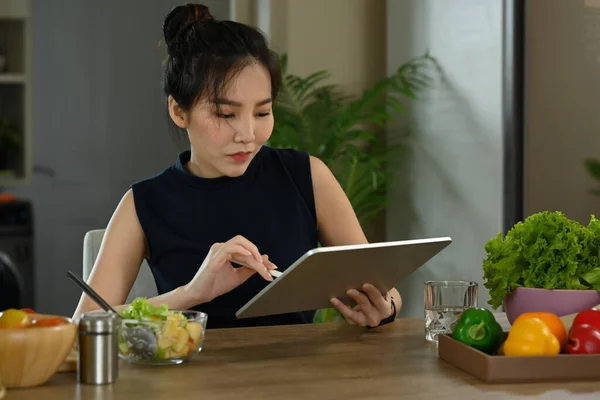 Όμορφη Νεαρή Γυναίκα Χρησιμοποιώντας Ψηφιακή Ταμπλέτα Και Τρώγοντας Χορτοφαγική Σαλάτα — Φωτογραφία Αρχείου