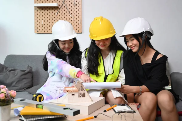 三个戴着安全帽的亚洲女孩一边在客厅里玩耍 一边假装是工程师 — 图库照片