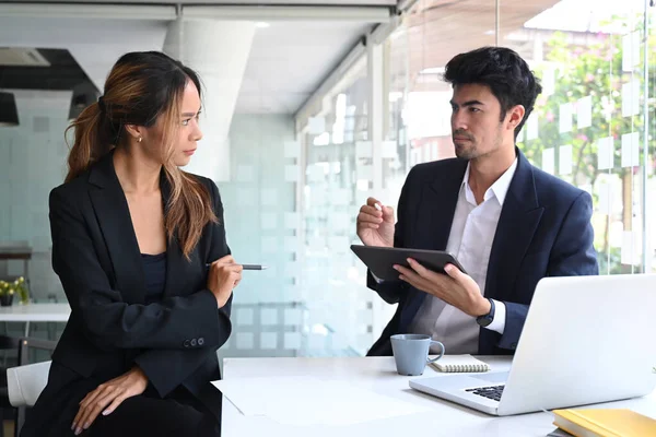 Dijital tablet tutan ve proje detaylarını meslektaşına açıklayan kendine güvenen bir işadamı.