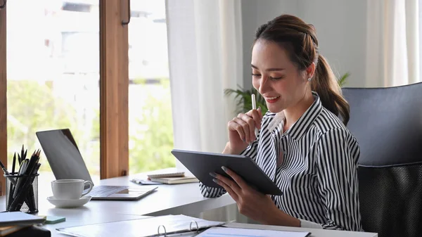 オフィスのデスクでインターネットで働いている間 幸せな若いビジネス女性起業家はデジタルタブレットを使用して — ストック写真