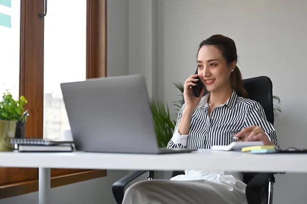 Urocza Kobieta Przedsiębiorca Siedzi Biurze Laptopem Rozmawia Przez Telefon Komórkowy — Zdjęcie stockowe