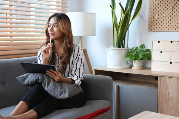 Tatmin olmuş bir kadın rahat koltukta dinleniyor ve dijital tablet kullanıyor..