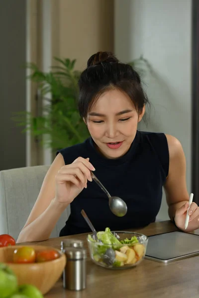 漂亮的年轻女人坐在家里厨房里吃蔬菜沙拉 饮食与健康食品概念 — 图库照片