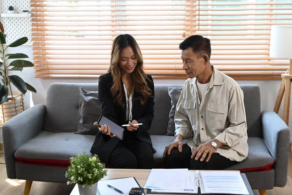 Kadın sigorta acentesi, ofisteki yaşlı müşterilere sağlık sigortasının detaylarını sunuyor..