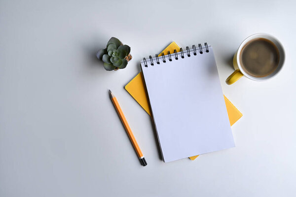 Notebook, coffee cup, pencil and succulent plant on white table. Flat lay.