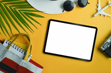 Gezgin aksesuarları, tropikal palmiye yaprağı dalları ve sarı arka planda dijital tablet. Yaz arkaplanı.