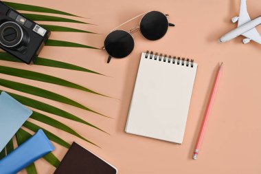 Gezgin aksesuarları, defter, güneş gözlüğü, kamera ve güneş kremi şişeleri. Seyahat, yaz ve tatil konsepti.