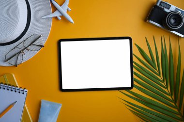 Dijital tablet, şapka, retro kamera, gözlükler ve sarı arka planda tropikal palmiye yaprakları. Yaz tatili kavramı.