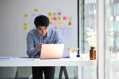 Genç erkek web sitesi geliştiricisi yaratıcı iş yerinde web cep telefonu için uygulama geliştirmeyi planlıyor.