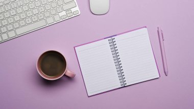 Mor arka planda boş bir defter, kahve fincanı ve kalem vardı..