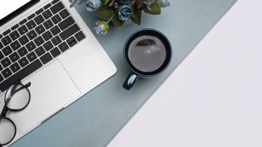 Dizüstü bilgisayar, bardaklar, kahve fincanı ve saksı beyaz masada. Üst görünüm.