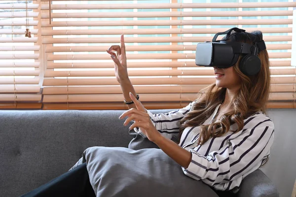 Egy Fiatal Virtuális Valóság Headset Visel Kanapén Ülve Megérint Valamit — Stock Fotó