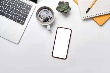 Sıralı ekran, dizüstü bilgisayar, kahve fincanı ve not defteri beyaz ofis masasında.