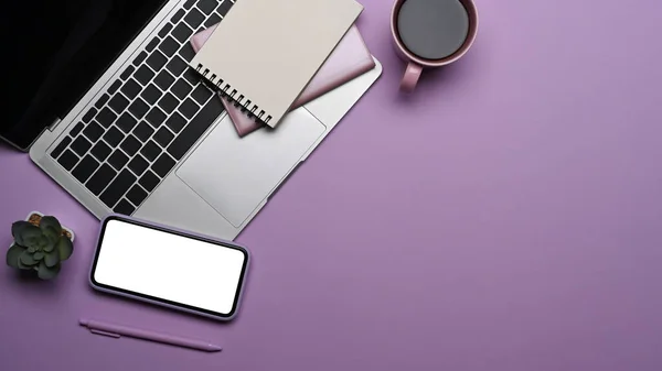 Smartphone with white screen laptop computer, coffee cup and notebook on purple background. Flat lay. — Fotografia de Stock