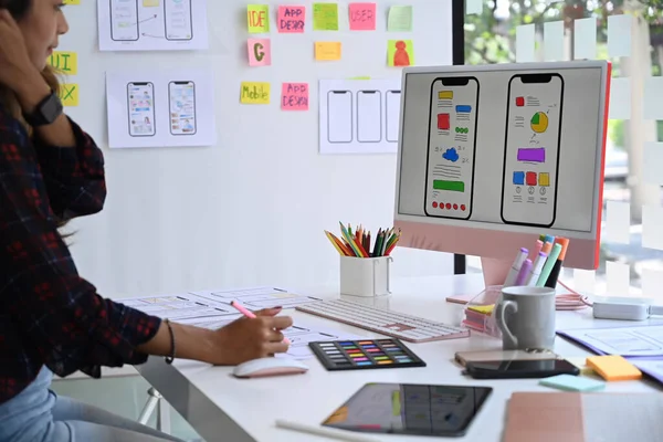 Young female website designer working in a studio to create application for mobile phone. — Foto de Stock