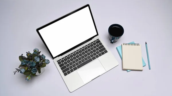 Computer laptop, coffee cup, notepad and flower pot on white table. Top view. — Zdjęcie stockowe