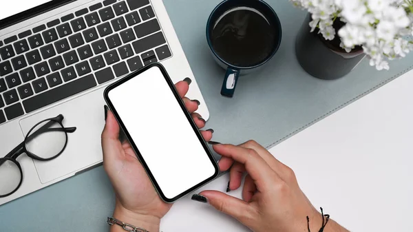 Manos de mujer sosteniendo teléfono móvil con pantalla blanca en su escritorio de oficina. — Foto de Stock