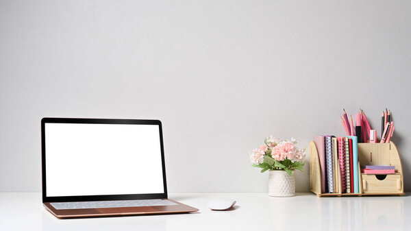 Laptop computer with empty screen and supplies on white table