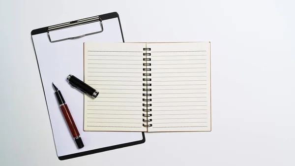 Notebook, clipboard ad pen on white office desk. Top view — Foto Stock