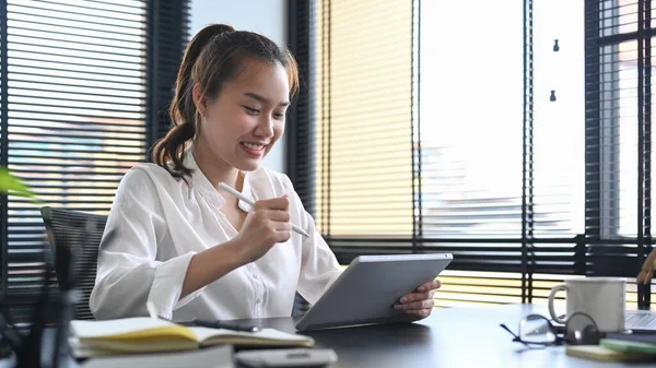 Młoda pracownica biurowa siedzi w nowoczesnym biurze i korzysta z tabletu cyfrowego — Zdjęcie stockowe