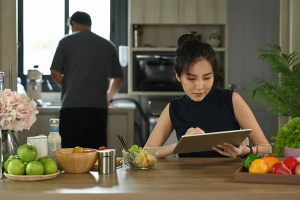 Asiática dona de casa sentado em casa e navegar na internet no tablet digital. — Fotografia de Stock