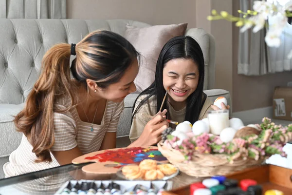 Mother drawing her daughter face while painting Easter eggs together. — 스톡 사진